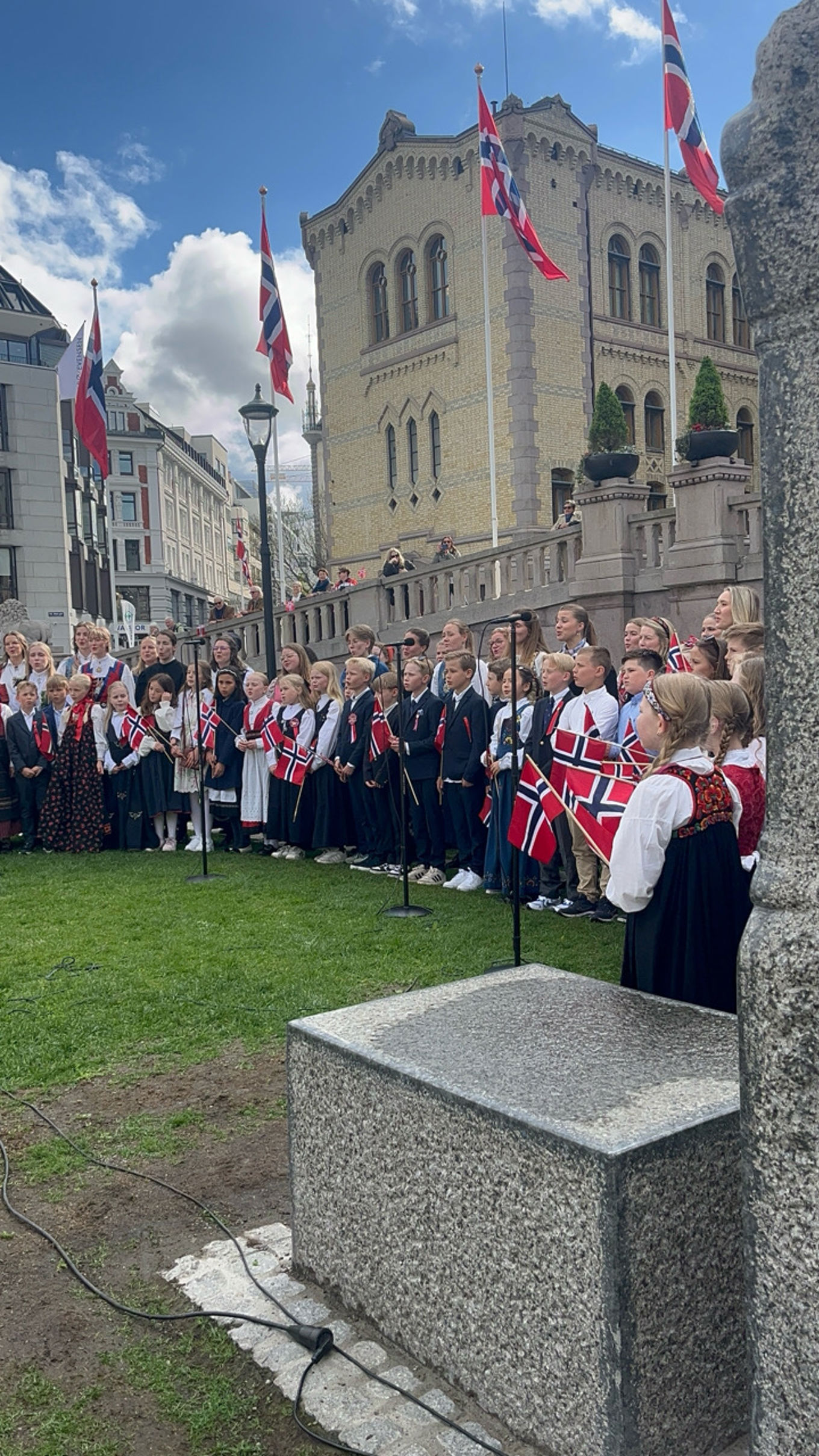 en gruppe mennesker i festklær foran Stortinget 
